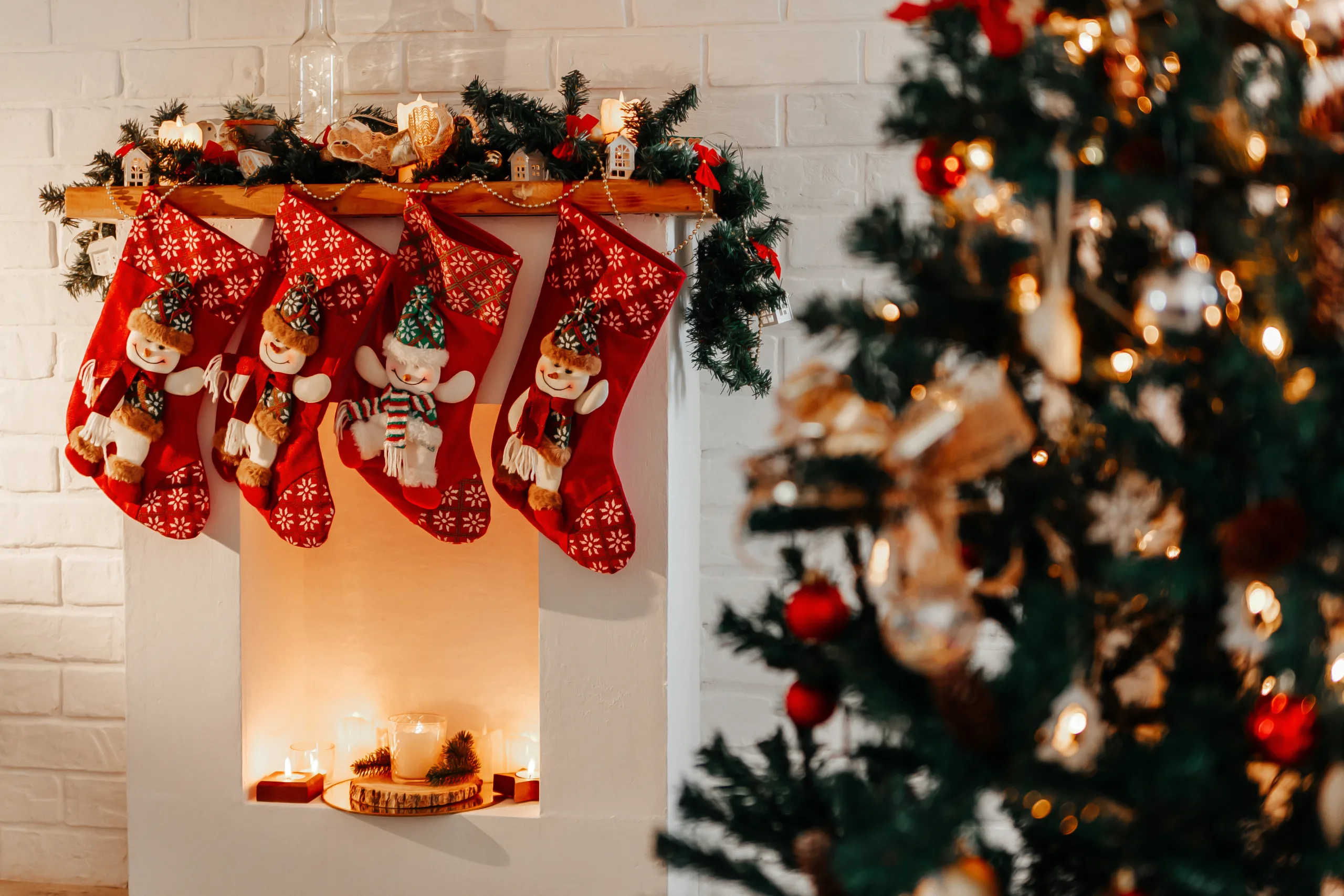 Four Christmas Red Socks Hanging On White Fireplace In Room.