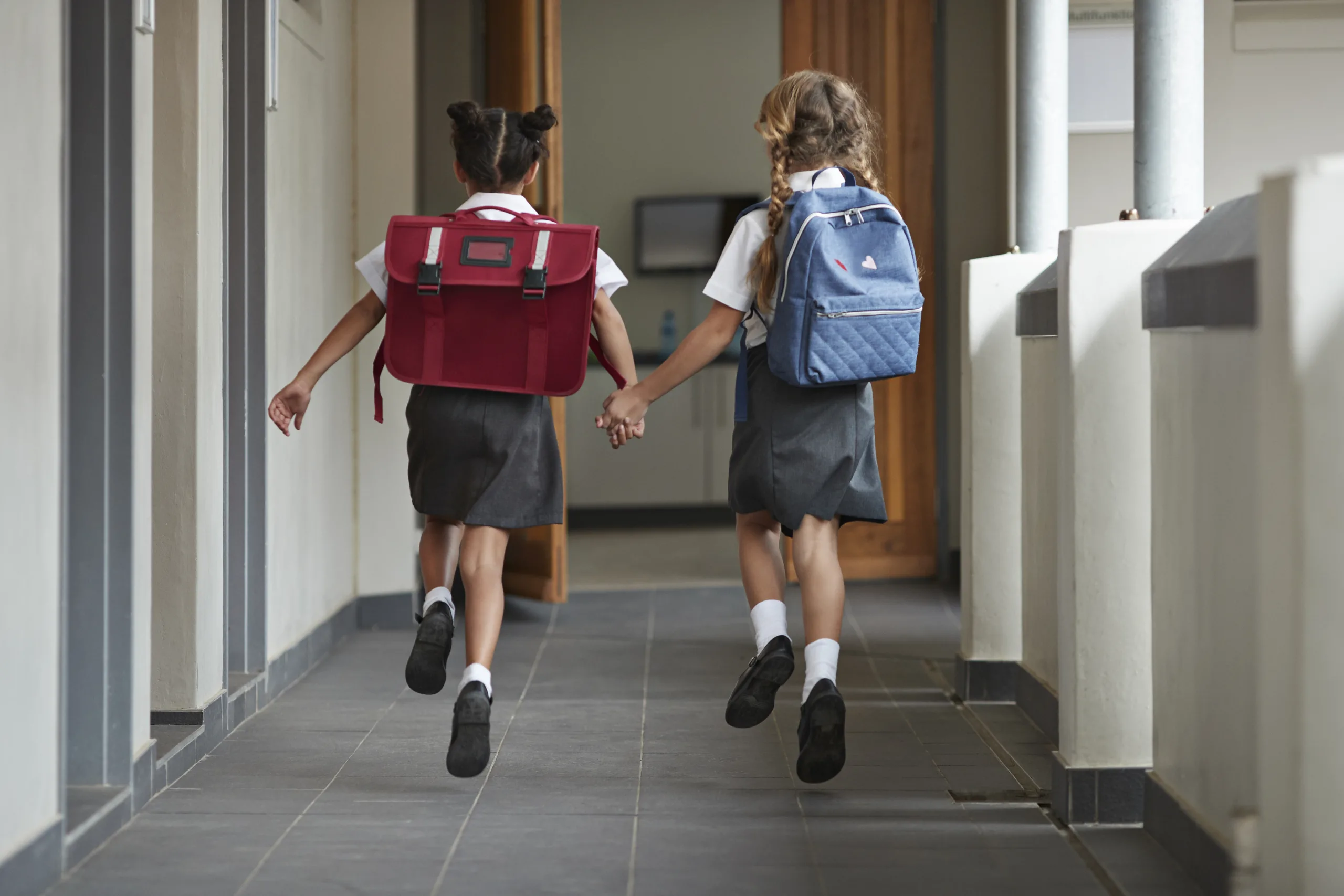 Schoolgirls Running Hand In Hand On The Isle Of School And Laughing