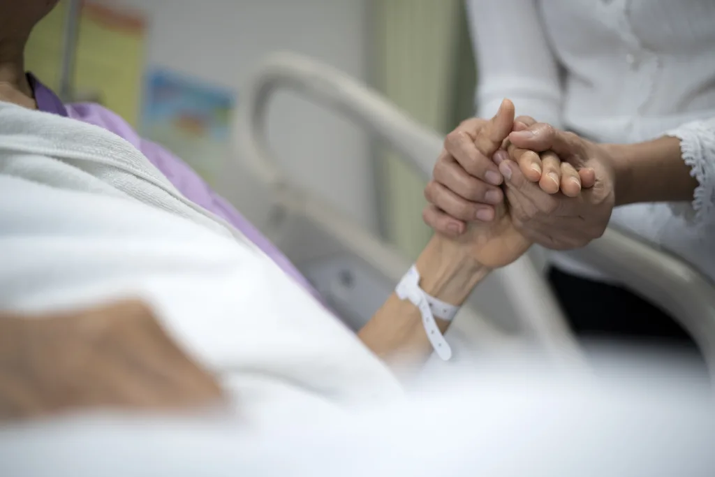 Shot Of Daughter Encourage Her Mother And Holding The Mother's Hand To Sleep On The Bed in Hospital.